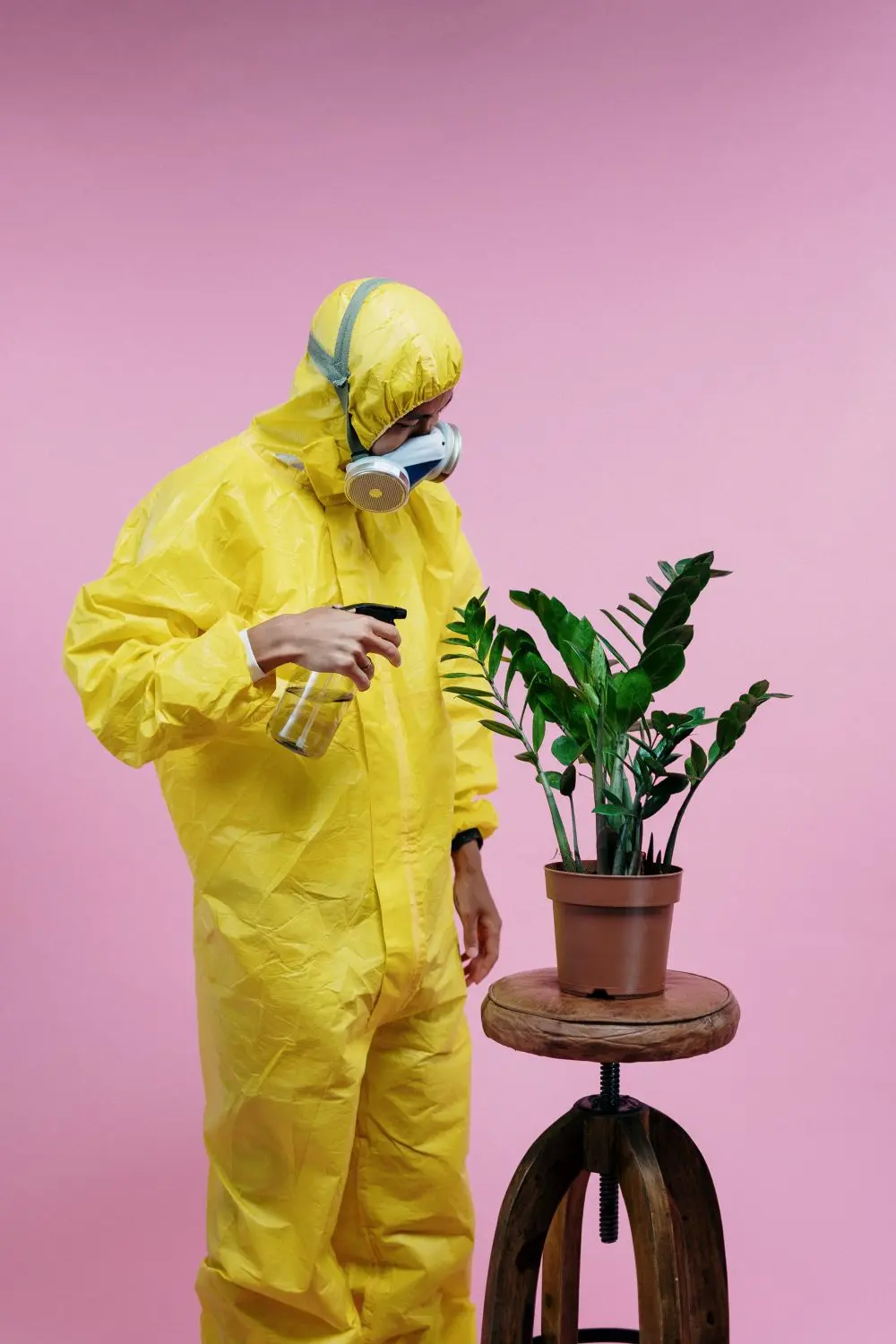 A technician in a yellow suit and respirator next to a spray.